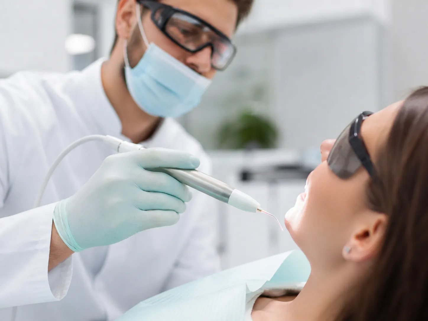 A dentist using a dental laser handpiece during a calm treatment demonstration